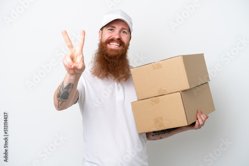 Delivery reddish man isolated on white background smiling and showing victory sign