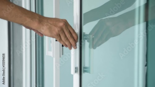 Close-up of man's hand clossing a glass door with a key.