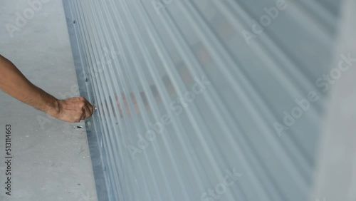 Close-up of man's hand using a key to open a rolling iron door.