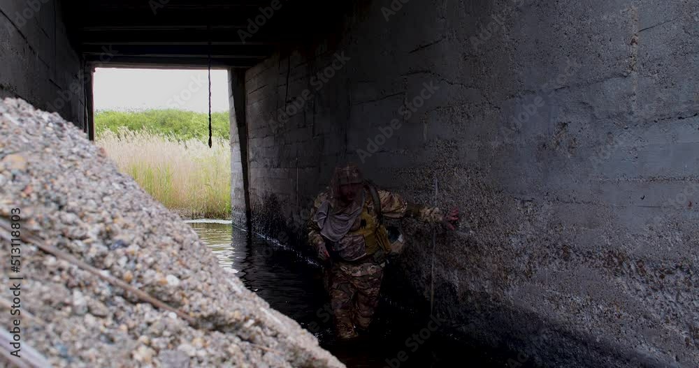A special forces soldier sneaks along a partially flooded tunnel, fires two shots from a pistol and hides behind a wall. A special forces soldier sneaks along a partially flooded tunnel, fires two shots from a pistol and hides behind a wall.