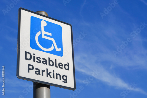 Disabled parking space sign against a clear blue sky.