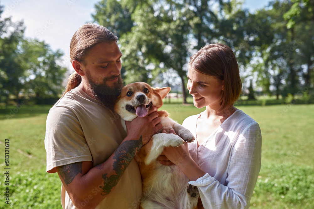 Couple holding and caressing Corgi dog in park Couple holding and caressing Corgi dog in park