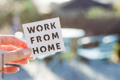 work from home sign being hold in front of sunny out of focus backard, digital nomads working remotely or wfh days during lockdowns photo