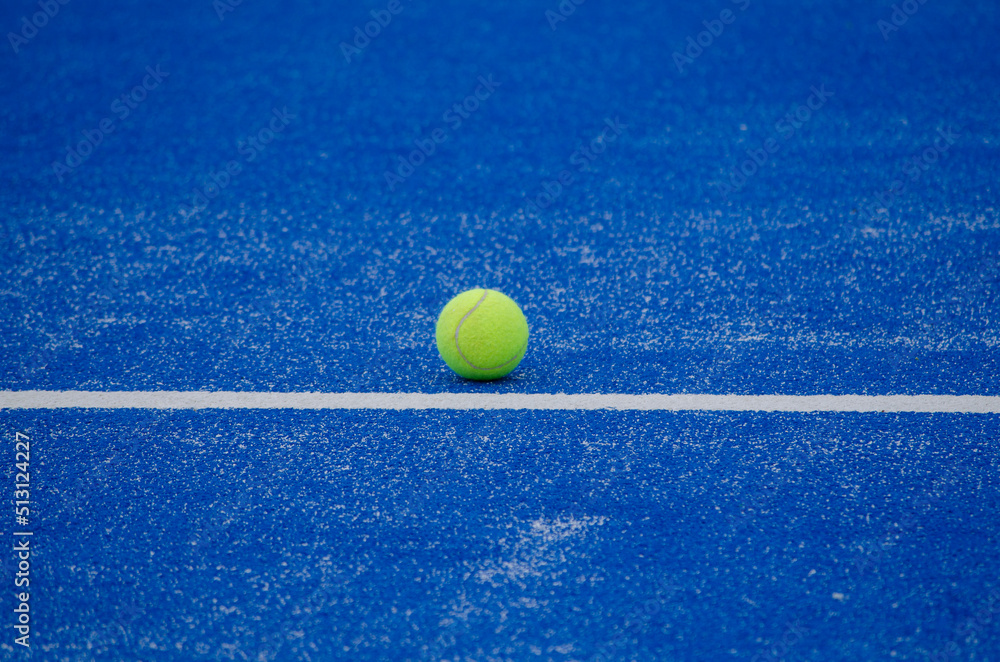paddle tennis ball on the line of a blue paddle tennis court, racket sports concept