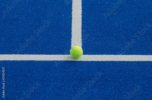 paddle tennis ball on the line of a blue paddle tennis court, racket sports concept © Vic