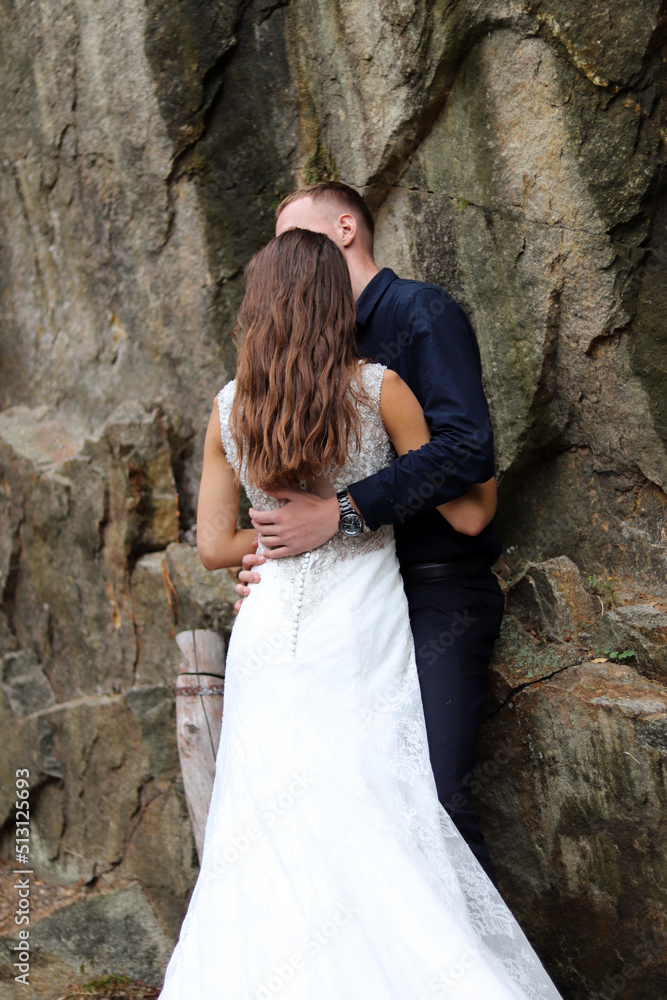 Happy wedding couple kissing and hugging near a high cliff.