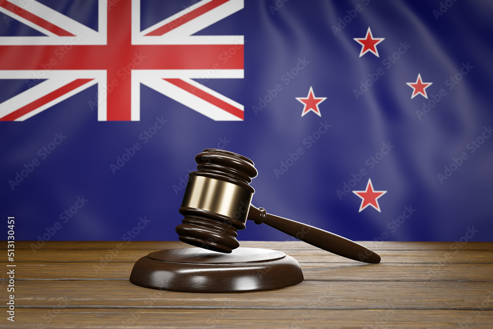 Small hammer gavel of judges of courts placed on a wooden table with New Zealand flag as background.