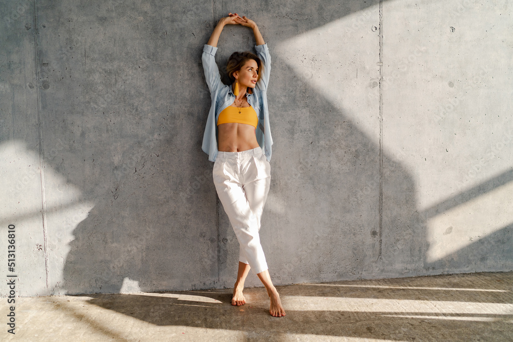 Fototapeta premium smiling happy beautiful woman posing against concrete wall on sunny day summer fashion style trend