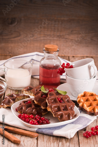Waffles with chocolate topping, red currant and hazelnuts.