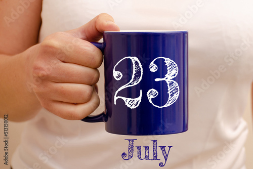 The inscription on the blue cup 23 july. Cup in female hand, business concept