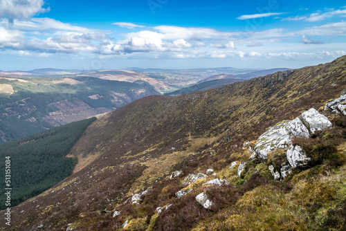 View of Glenmalure valley during sunny day. It is U-shaped glacial valley in the Wicklow Mountains in Ireland. Base for accessing the mountain of Lugnaquilla. Saturated colors and dramatic sky.