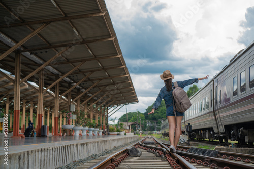 Asian woman balancing on the train rail. Attractive young woman walking outdoors.