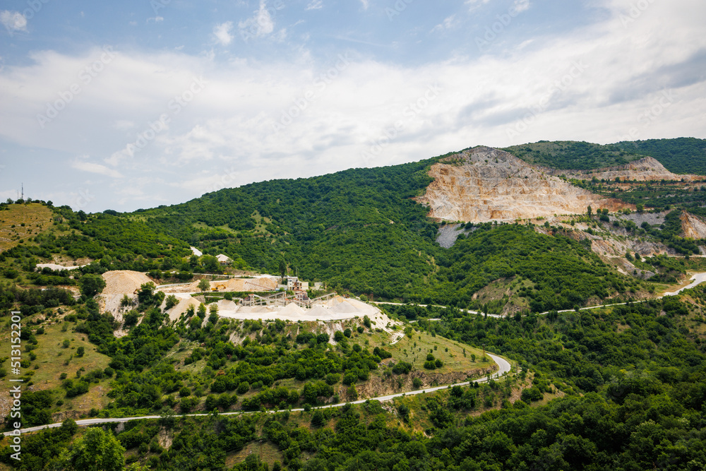 Quarry for extraction of minerals with equipment and machines, and road, in Rhodope Mountains covered with forests