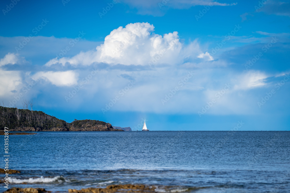 Yacht sailing on the horizon near the beach on the ocean at Hobart, Tasmania, Australia Yacht sailing on the horizon near the beach on the ocean at Hobart, Tasmania, Australia