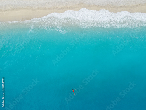 Aerial view of woman in red bikini swims in the sea
