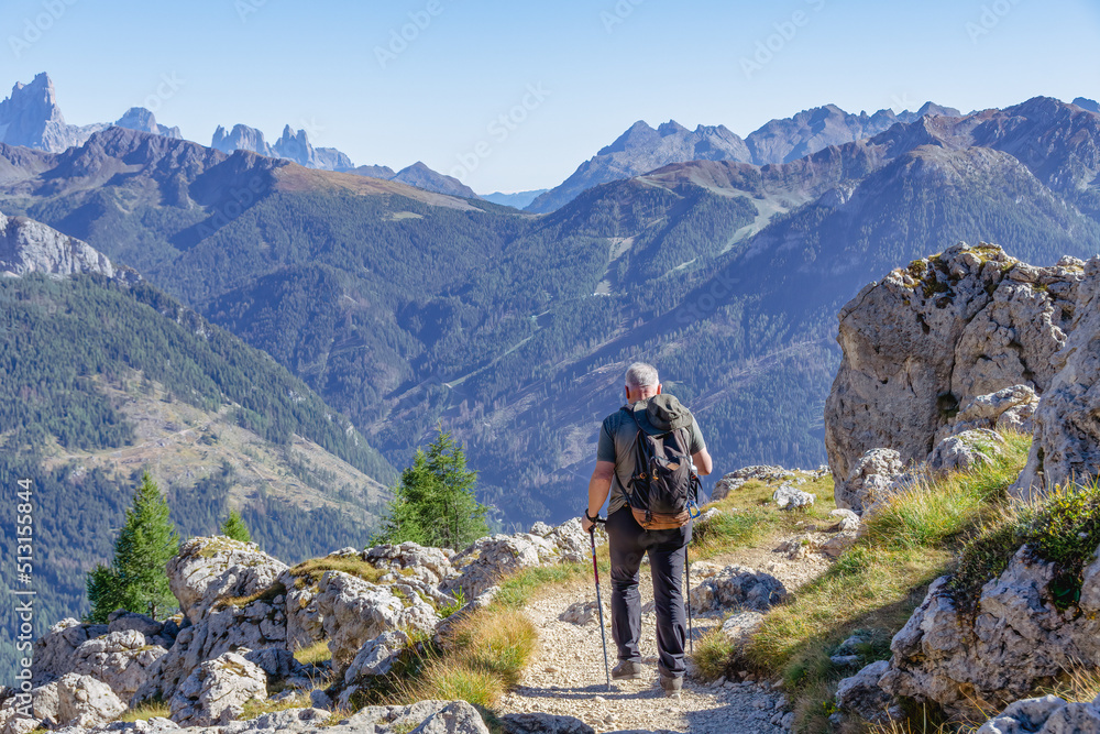 Active senior man hiking in Dolomiti mountains with backpack, enjoying his adventure. Carezza, Dolomites Alps, South Tyrol, Italy, Europe.