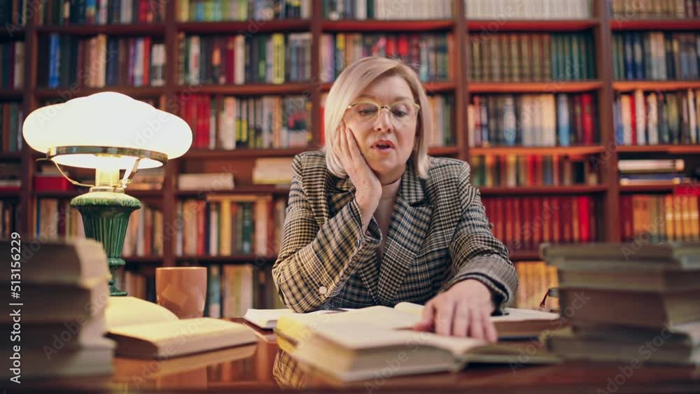 Mature woman tired from overtime work in library, journalist studying archives Mature woman tired from overtime work in library, journalist studying archives