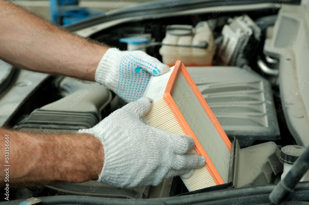 Car parts. Air filter for the engine.An auto mechanic installs a new air filter during car maintenance at a service station.