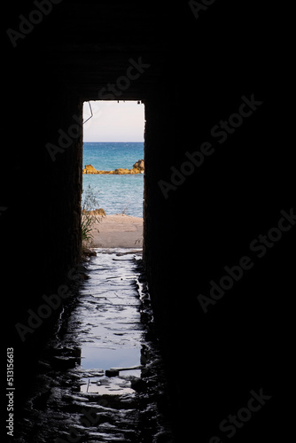 Afternoon view through an opening of an underpass of the rocks and beach around Petra tou Romiou, in Paphos, Cyprus.