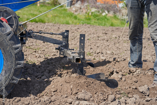 farmer plows the field,hilling the ground with a two-wheeled tractor