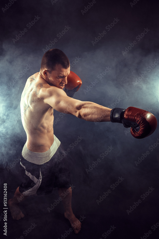 Muscular kickbox or muay thai fighter punching in smoke