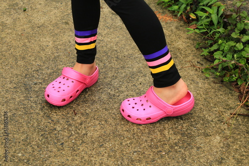 Girl wearing pink plastic slippers.