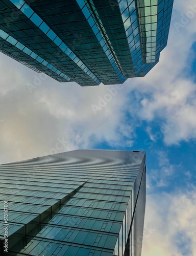 Photography Vertical low angle shot of beautiful skyscrapers against a blue sky in downtown