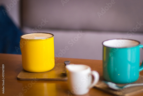 Coffee cups and milk saucer on table. Coffee break. Idyllic place for work. Morning with coffee. Creative space for work. Hot morning drinks. Colorful cups with cappuccino.