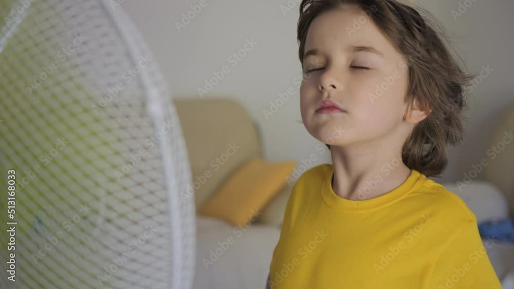 Child Enjoying Cool Wind From Electric Fan at Home at Summer Heat. Suffer From Heat High