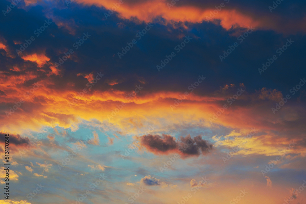 Cloudy sky at sunset. Dark blue and yellow natural background or wallpaper. The rays of the setting sun effectively illuminate the clouds. Beautiful colorful evening skies. Twilight cloudscape