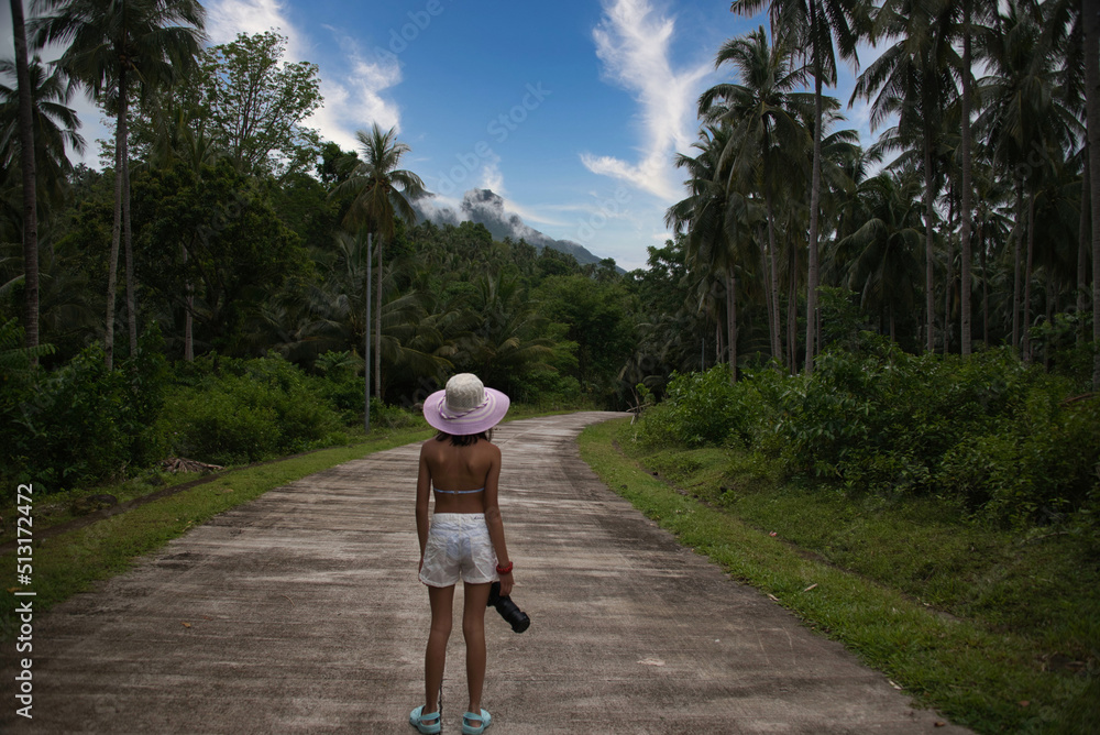 Niña asiatica caminando en el increíble paisaje tropical en la isla de Camiguin, Filipinas