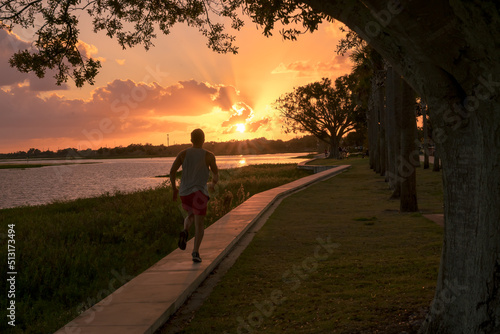 Young man running in a beautiful sunset by the lake. Sport concept