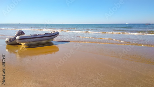 Rubber inflatable boat on the sandy shore of the sea on a sunny day © Tatiana Nikitina