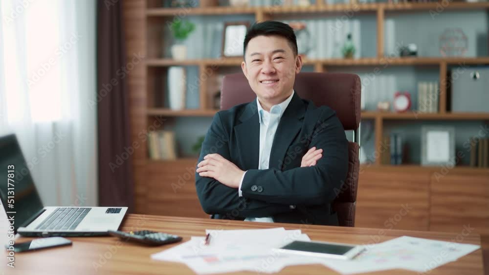 portrait happy asian business man in suit sitting at computer desk looking at camera at workplace smiling. indoor. successful Manager accountant, lawyer or banker bookkeeper, booker in a modern office portrait happy asian business man in suit sitting at computer desk looking at camera at workplace smiling. indoor. successful Manager accountant, lawyer or banker bookkeeper, booker in a modern office