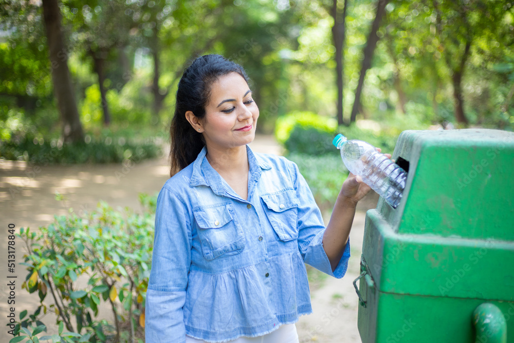 Indian woman throw empty litter in recycling bin, Asian female drop plastic bottle into garbage bin, pollution or waste management and save environment concept. - obrazy, fototapety, plakaty 