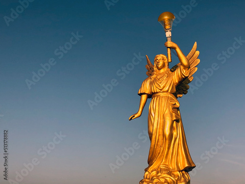 Angel statue standing against blue sky background.