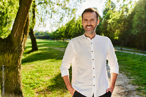 Portrait of smiling mid adult man standing at park during summer afternoon photo