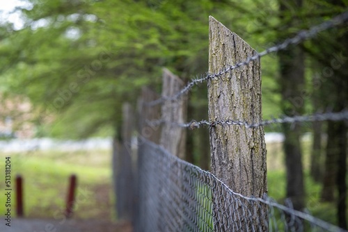 Perspective shot of a country wooden barrier with a metallic net in a blurry background. photo