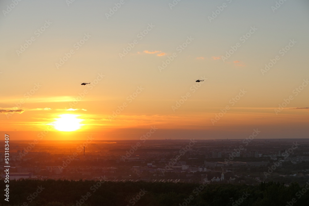 Two helicopters in the sky against the backdrop of the setting sun, Bright sunset. High quality photo
