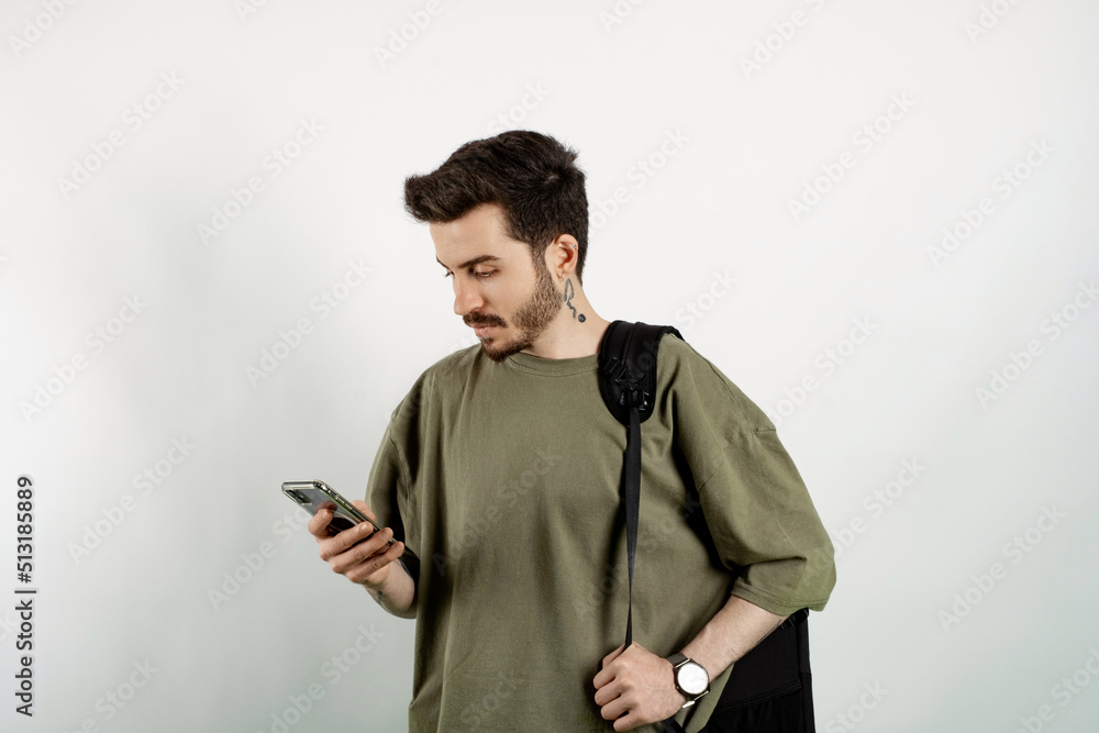 Handsome caucasian man wearing khaki t-shirt posing isolated over white background reading message on smart phone. Serious face.