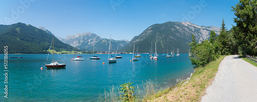 walkway along lake Achensee, many moored sailboats in the water. tirolean landscape