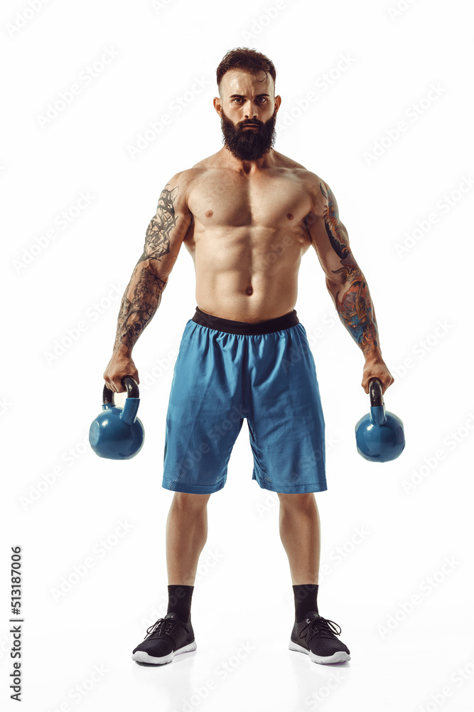 Muscular shirtless tattooed bearded male athlete bodybuilder workout with kettlebell on a white background. Isolate - obrazy, fototapety, plakaty 