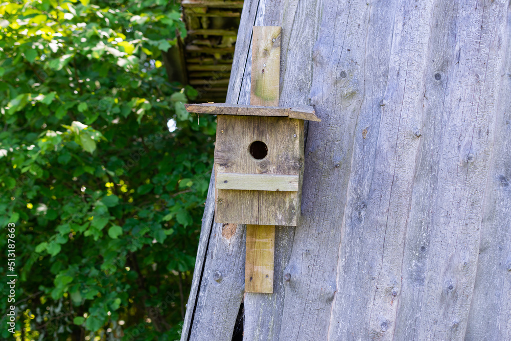 wooden barn with a wooden bird cage attached to the wall.