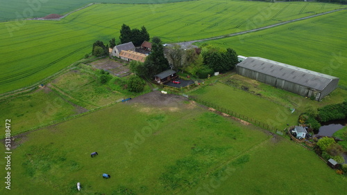 drone shot lush landscape horses and farmhouse