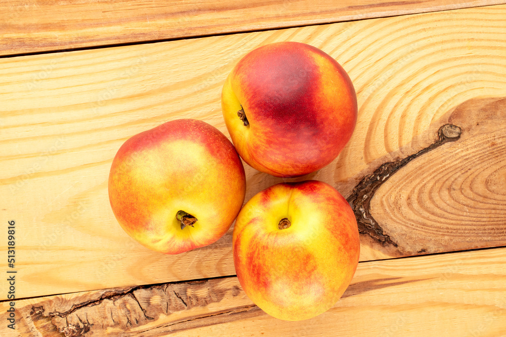Three ripe juicy nectarines on a wooden table, close-up, top view. Three ripe juicy nectarines on a wooden table, close-up, top view.