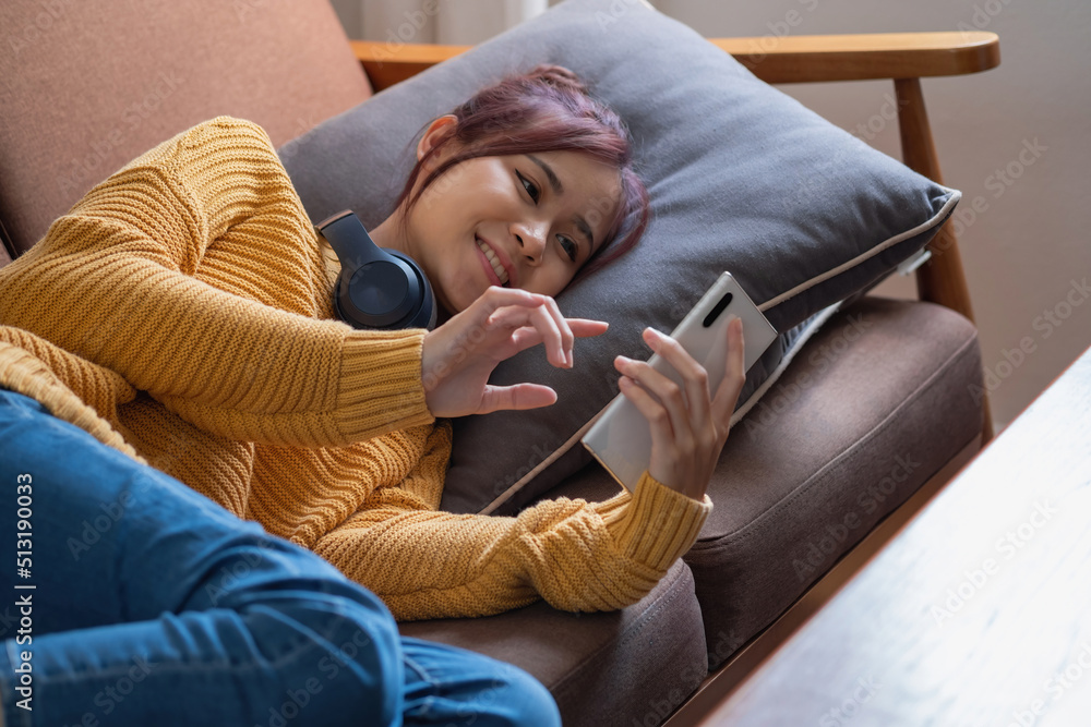 Obraz premium relax, de-stress, holiday, happy, Asian woman relaxing at home listening to music from smartphone and laptop happily.
