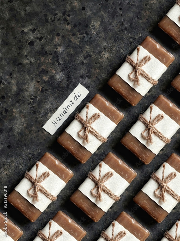 Pattern of handmade soap in craft paper tied with twine with a tag on rustic black background with copy space. Handmade tar soap background. Coffee soap. Pattern of handmade soap in craft paper tied with twine with a tag on rustic black background with copy space. Handmade tar soap background. Coffee soap.