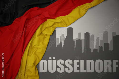 abstract silhouette of the city with text Düsseldorf near waving national flag of germany on a gray background. photo