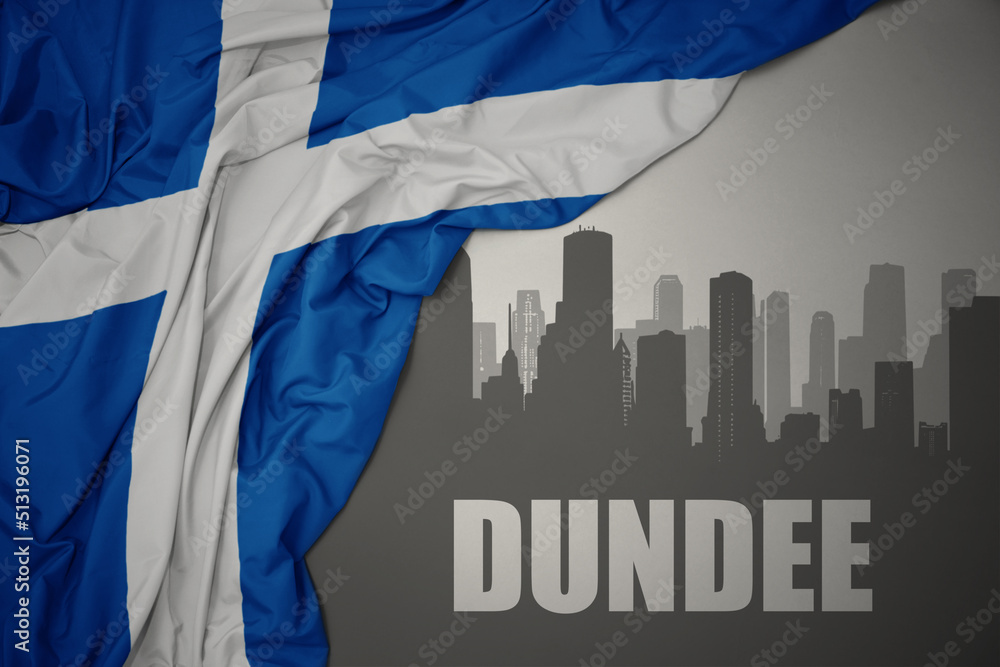 abstract silhouette of the city with text Dundee near waving national flag of scotland on a gray background.