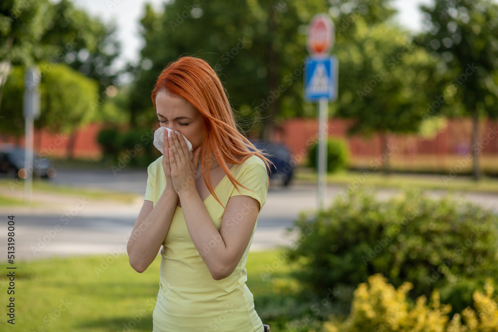 Fototapeta premium Young redhair woman sneezing in summer. Pollen Allergy symptoms